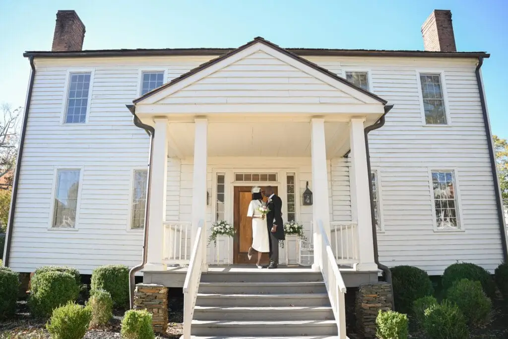 Atlanta classic venue wedding and couple posing in front door with big white house on background