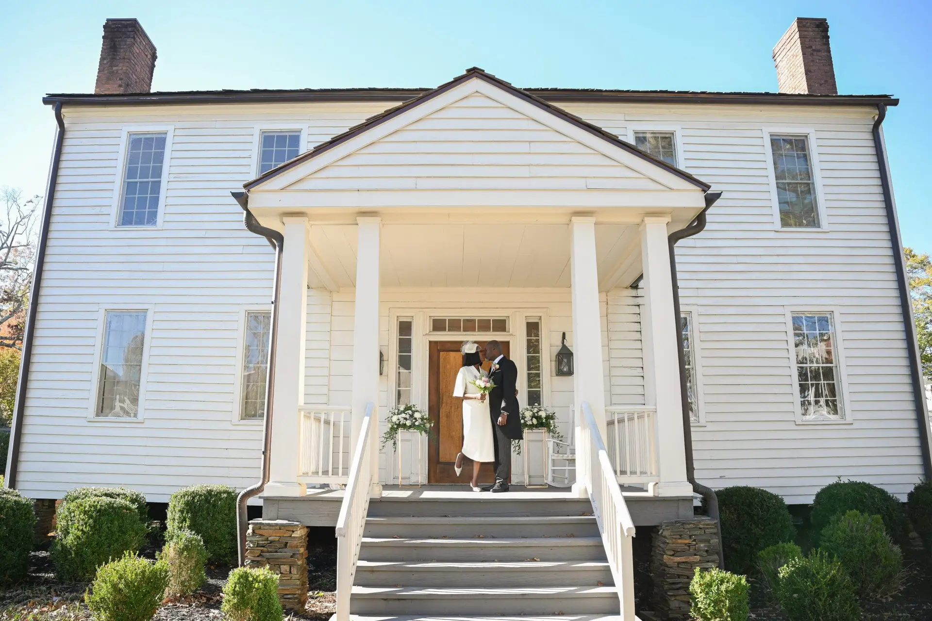 Atlanta classic venue wedding and couple posing in front door with big white house on background